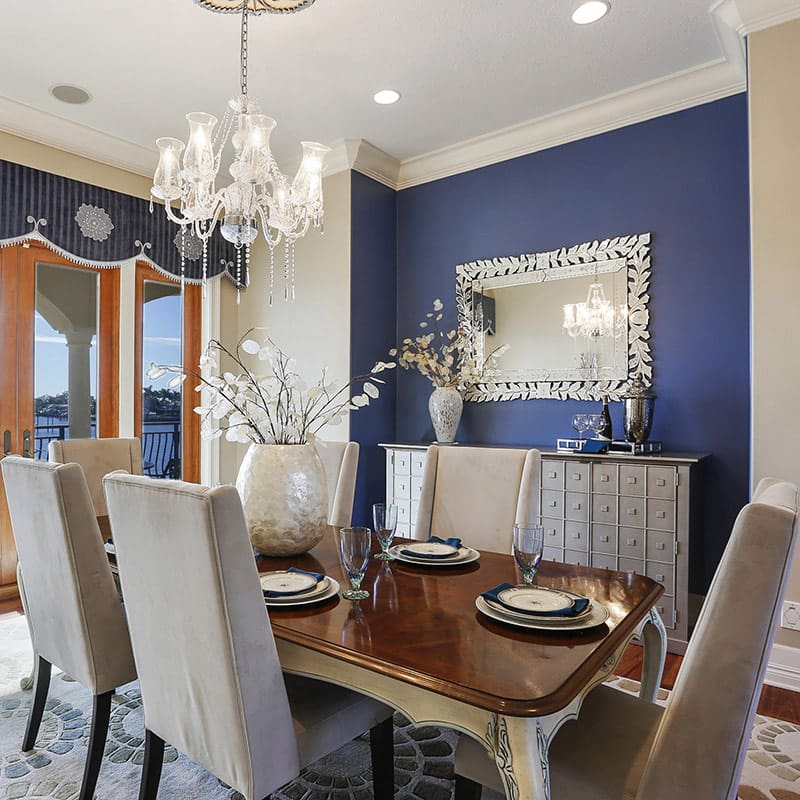 photo of a designer dining room with a blue accent wall and chandelier